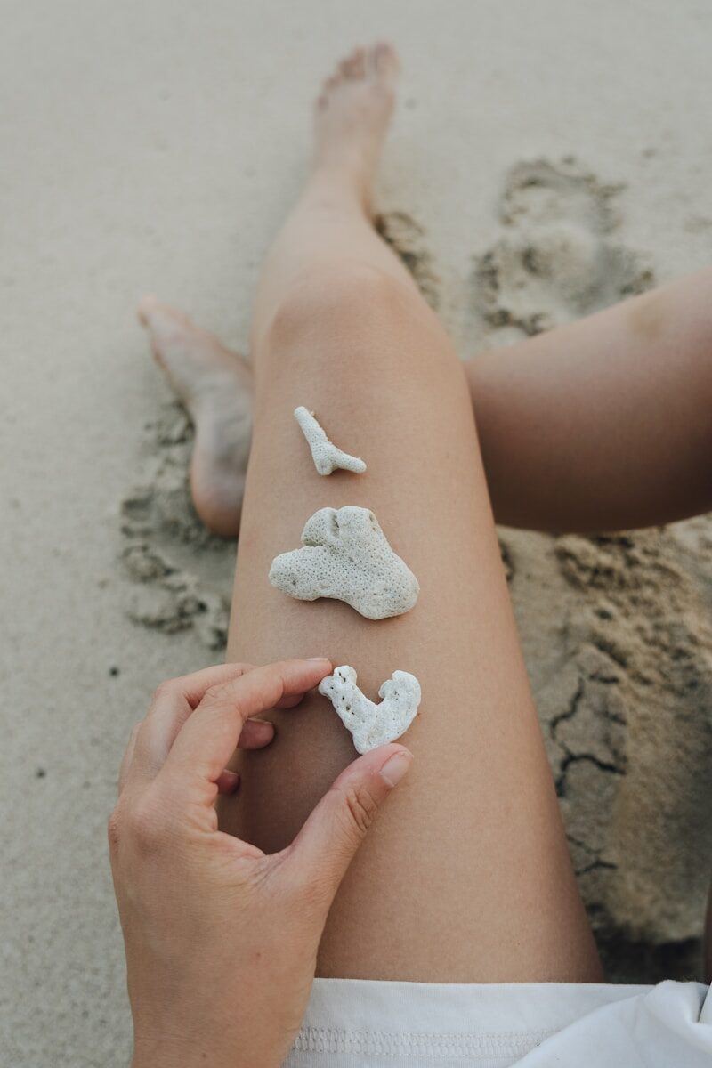 A person sitting in the sand with white sand on their legs
